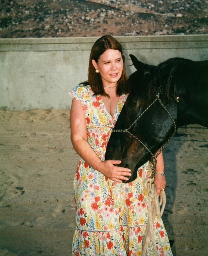 Andrea Jasso standing with a horse, her hand resting on its muzzle